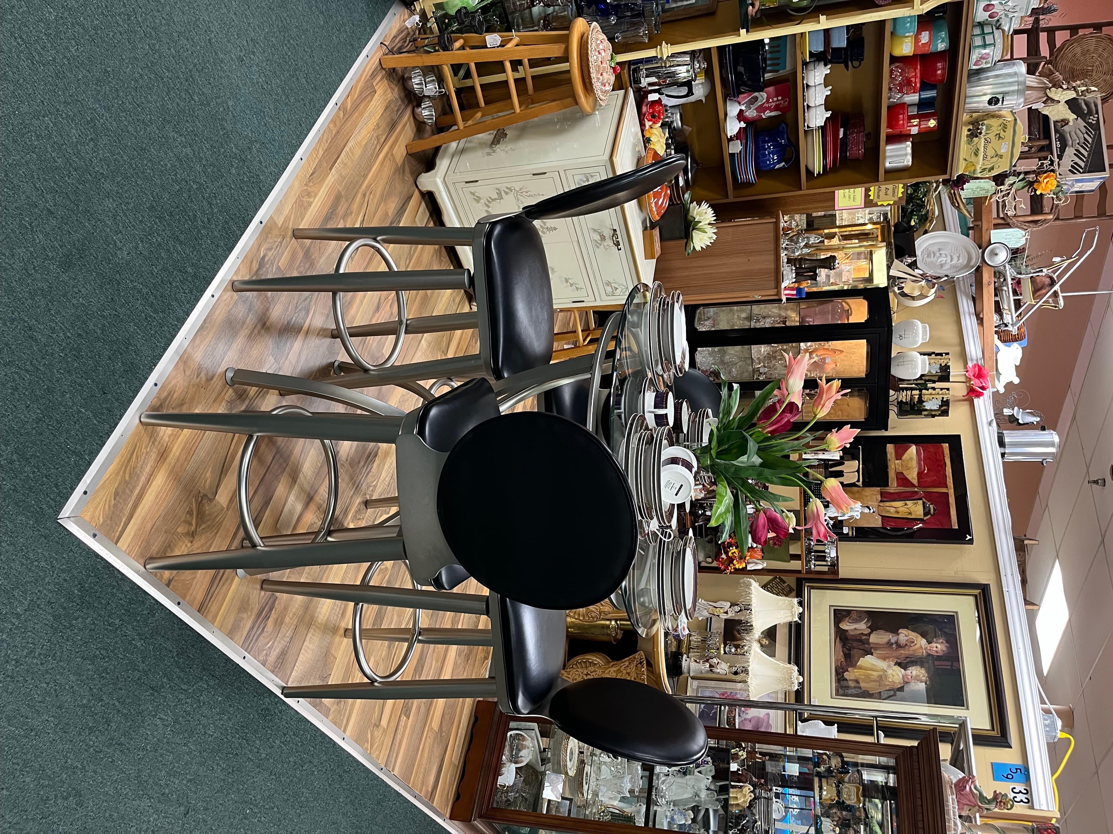 The Silk Purse Sisters booth — a small bistro table set with pink lilies in front of framed art and shelves of vintage finds.