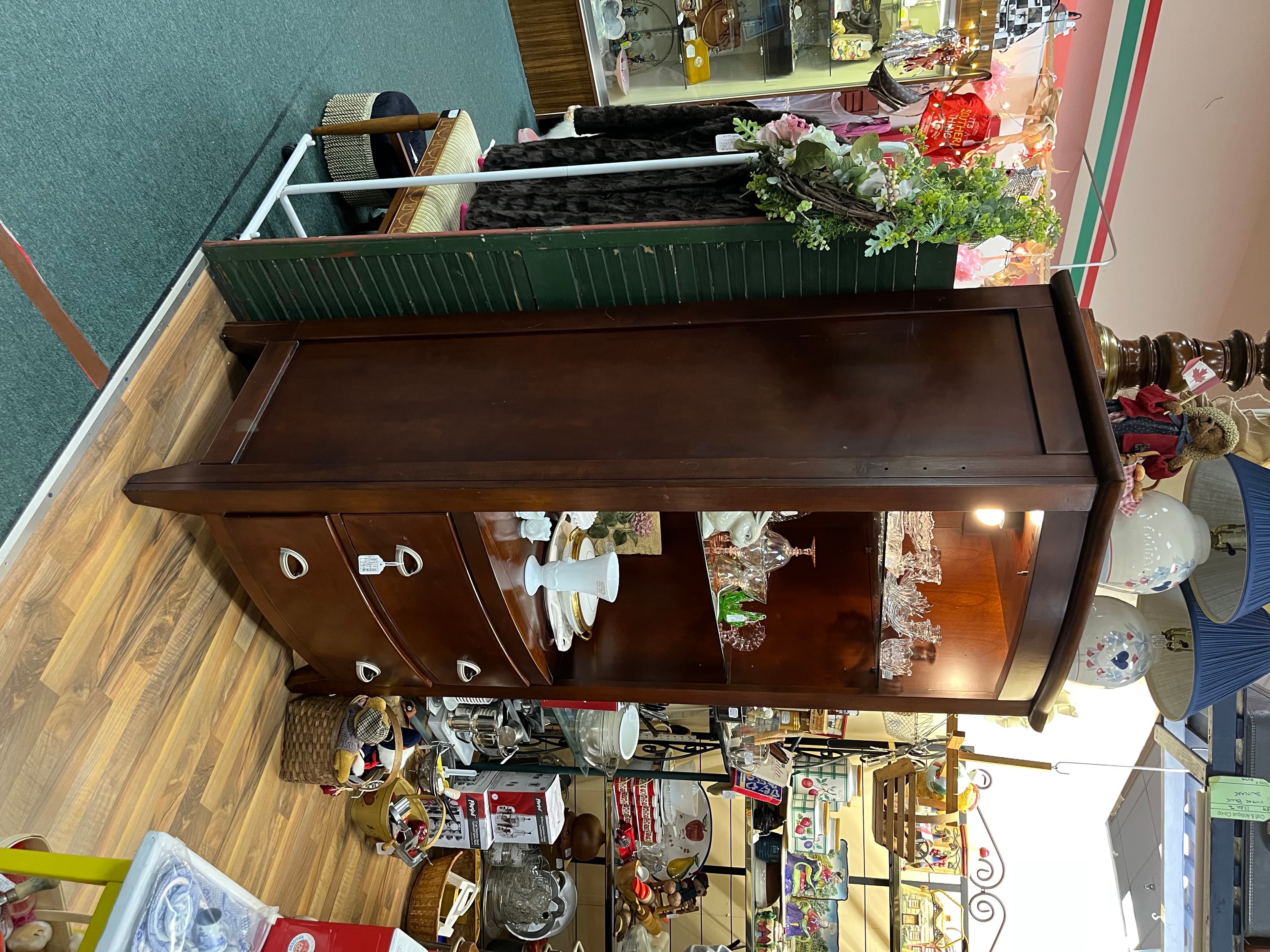 A walnut sideboard with carved drawers, set with vintage china and glassware.